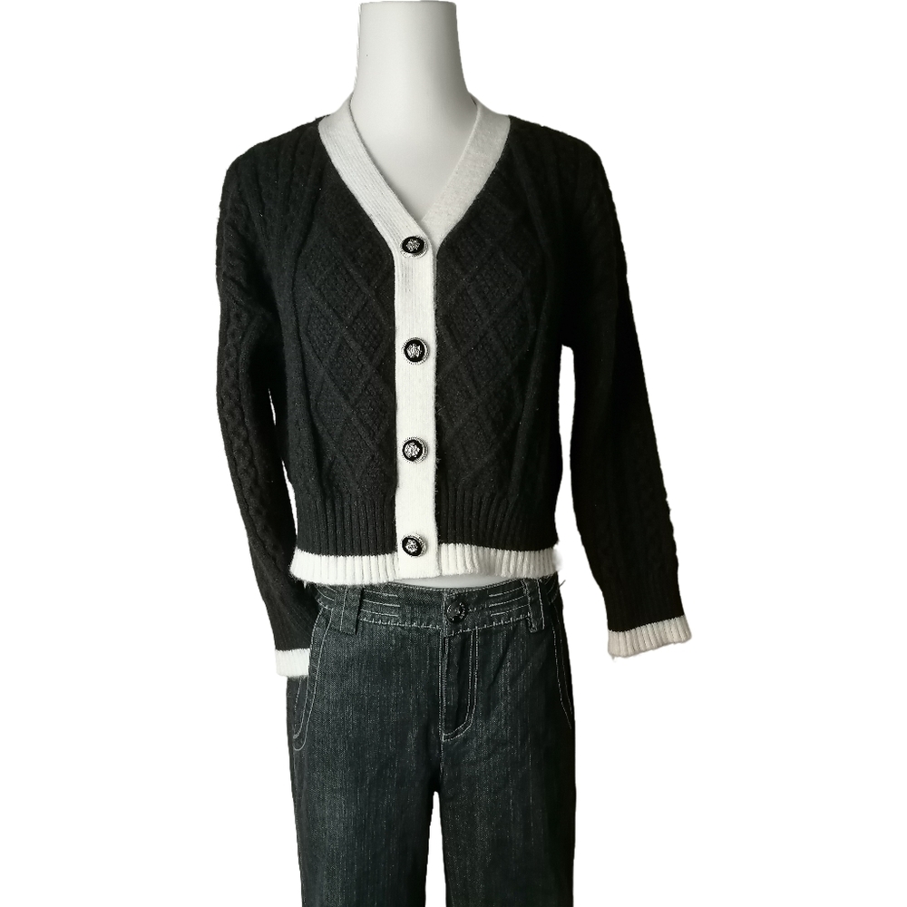 A cropped, cable-knit cardigan with a contrasting white collar, cuffs, and hem.